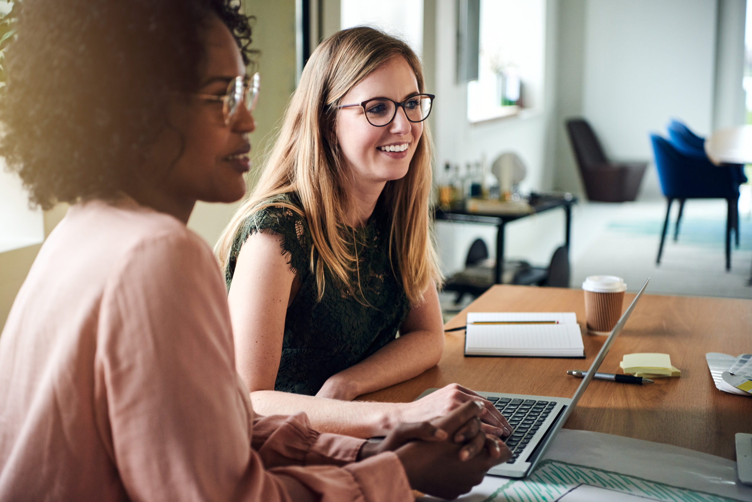 Two,Diverse,Female,Designers,Smiling,While,Working,Together,At,A